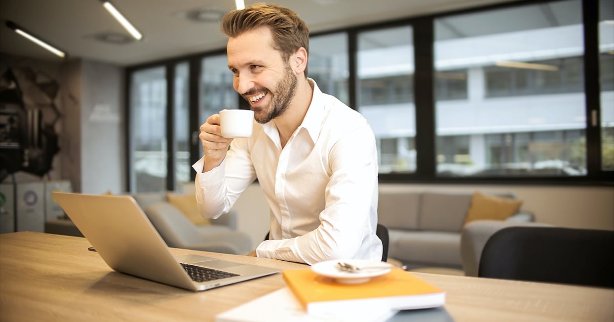 Person with laptop sipping at a coffee
